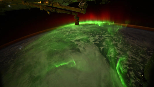 Green and red aurora snaking over the curve of the Earth, photographed from space